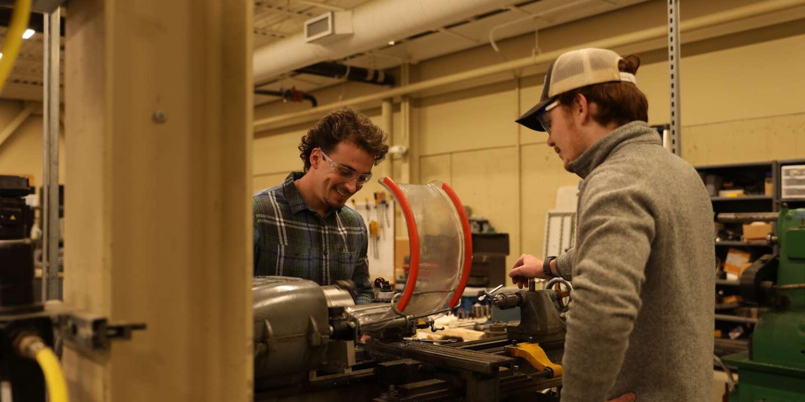 Two students working with machinery wearing safety goggles